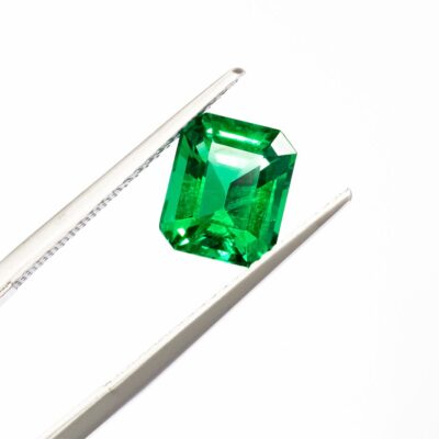 tweezers holding a precious green gem